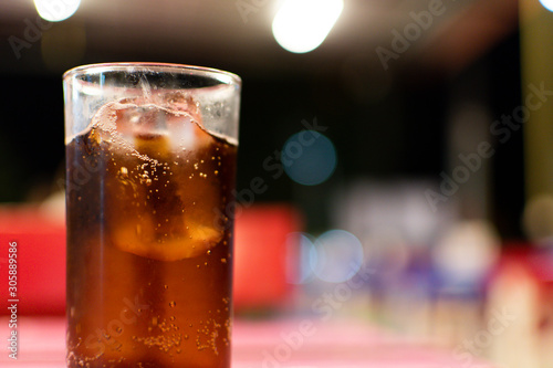 Soft drink glass placed on the table with the bokeh blur background.