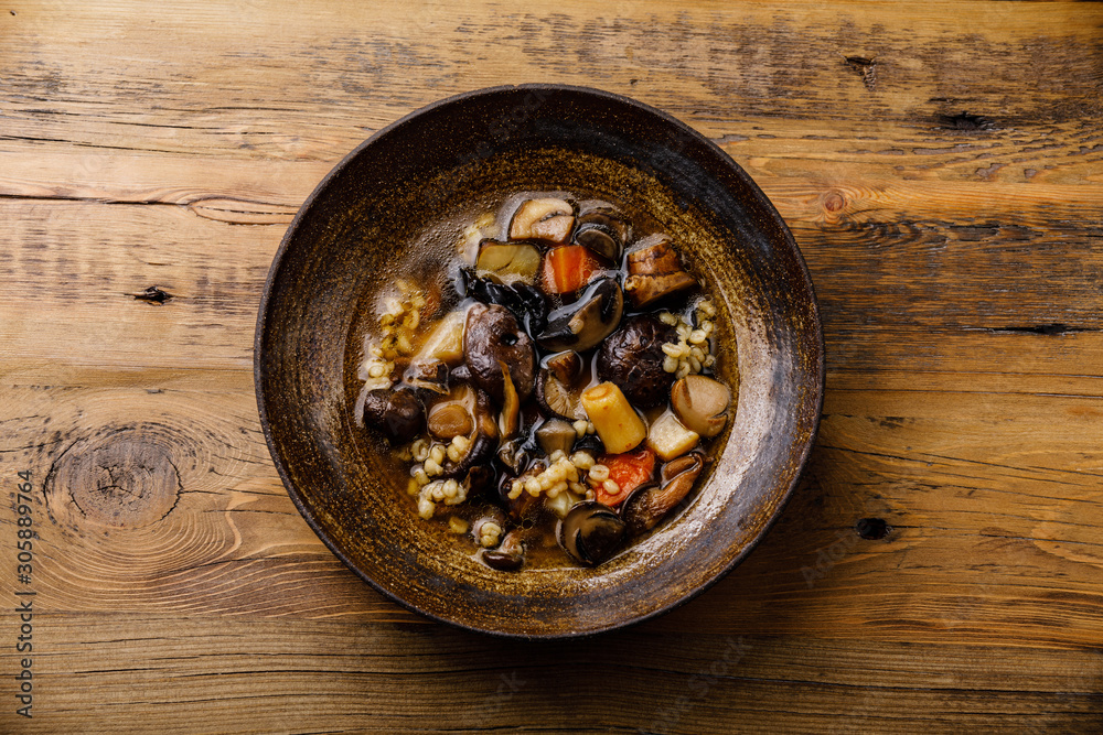 Fototapeta premium Healing Soup with roots, mushrooms and barley on wooden table background