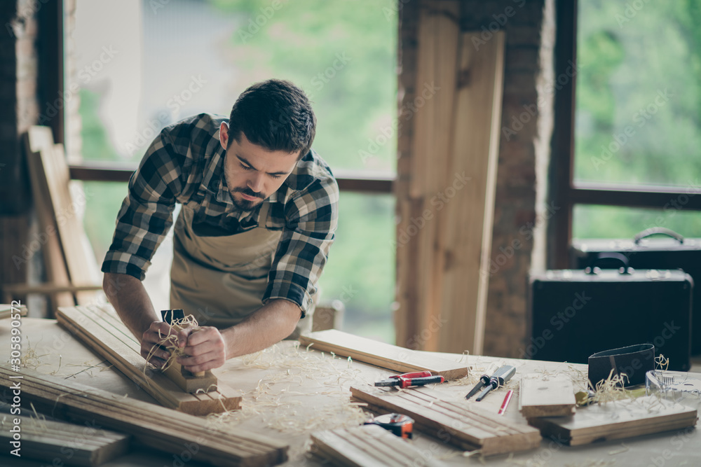 Portrait of his he nice attractive skilled hardworking guy creative self-employed engineer carving wood home-based studio manufacture at modern industrial loft brick style interior indoors