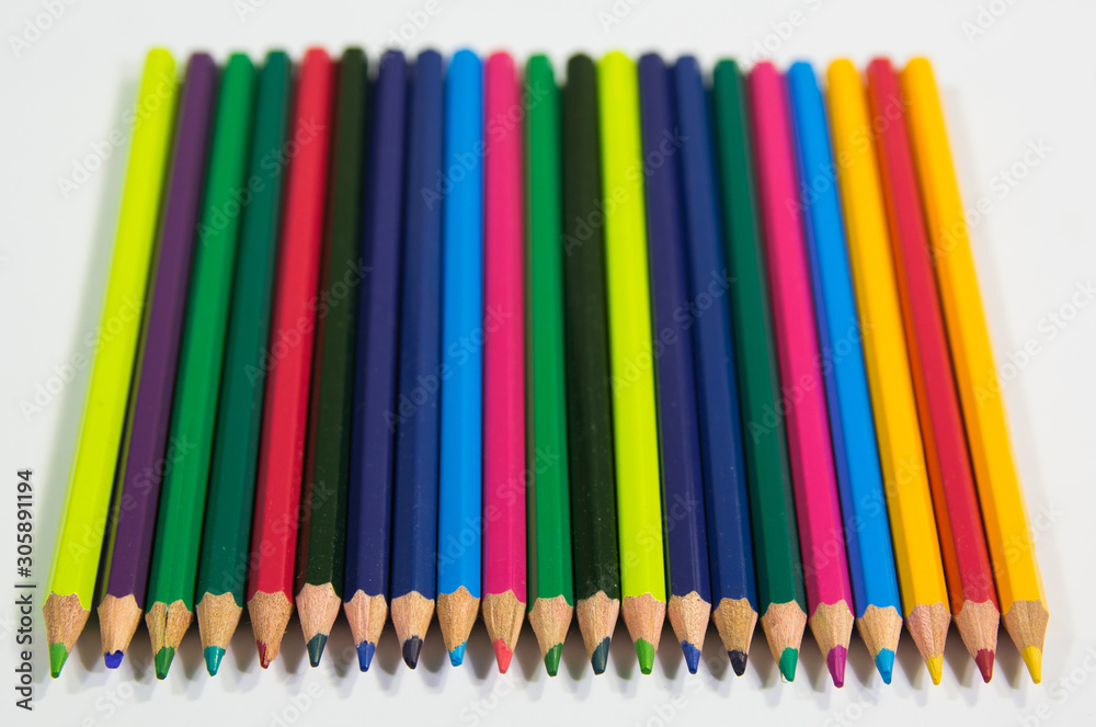 Top angle view of color pencils in line on a white background with front in focus Top angle view of color pencils in line on a white background with front in focus