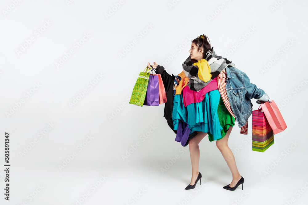 Shopping like an issue. Woman addicted of sales. Overproduction and crazy demand. Female model wearing too much colorful clothes, need more. Fashion, style, black friday, sale, abusing purchases.