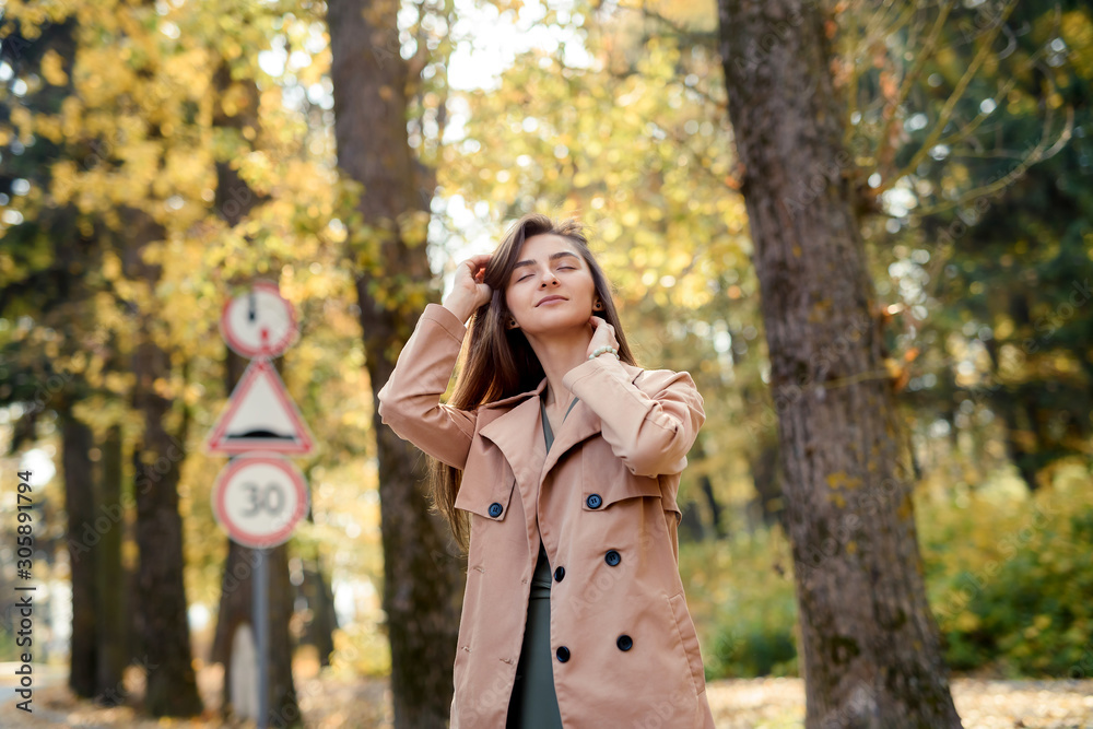 Autumn park. Beautiful woman in green dress posing in autumn park with yellow leaves