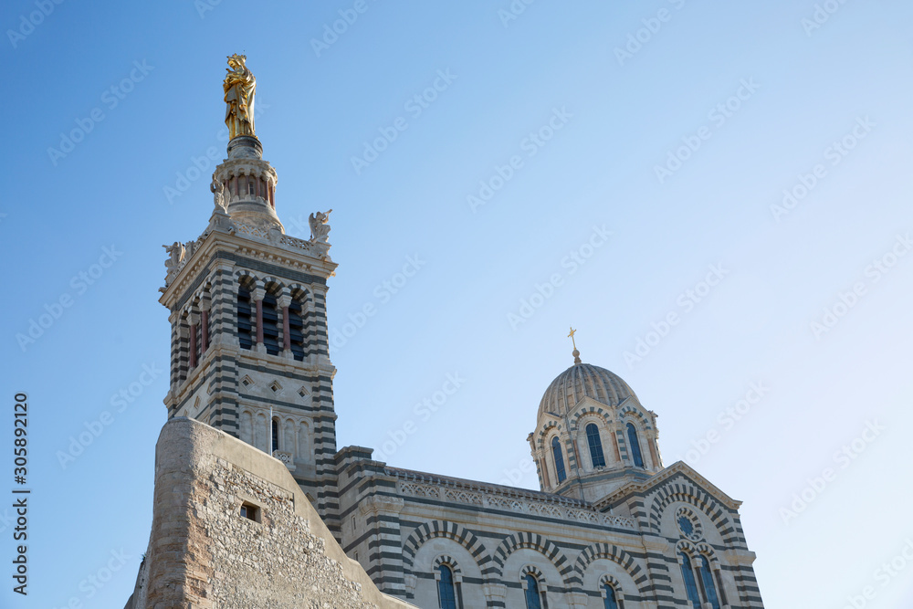 Fototapeta premium Beautiful view of Notre Dame de la Garde in Marseille against a bright blue sky on a sunny day.
