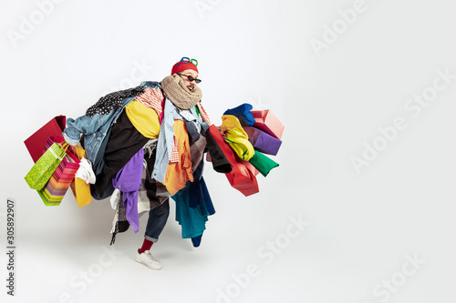 Shopping like an issue. Man addicted of sales. Overproduction and crazy demand. Female model wearing too much colorful clothes, need more. Fashion, style, black friday, sale, abusing purchases photo