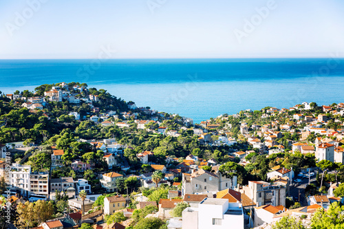 Beautiful top view of a European city on the coast of the sea. White houses with orange roofs, bright blue sky on a sunny day. Great landscape.