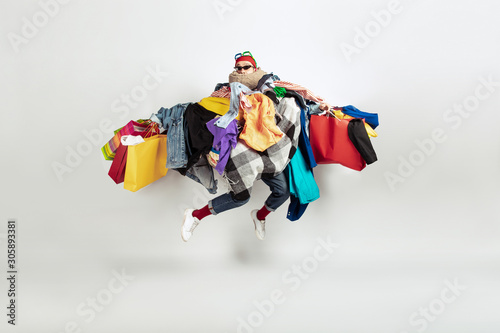 Shopping like an issue. Man addicted of sales. Overproduction and crazy demand. Female model wearing too much colorful clothes, need more. Fashion, style, black friday, sale, abusing purchases