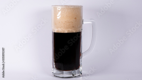 Beer glass with dark beer and foam on a white background
