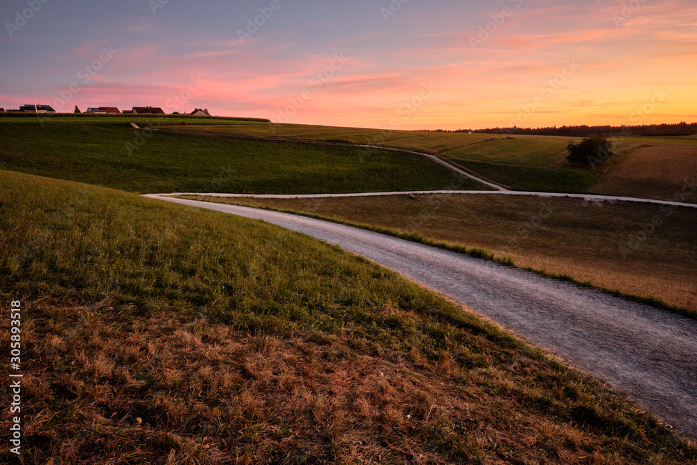 Beautiful countrsyside landscape during dusk with fields, meadows, gravel roads and some houses on the horizon. Seen in late summer in Franconia / Bavaria, Germany near Kalchereuth
