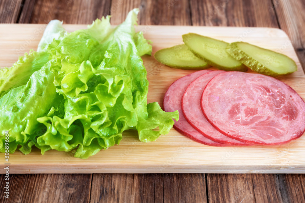 Meat, green salad and pickles on cutting Board on wooden background.