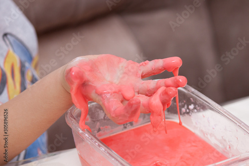 Fotografía Closeup of kids hand holding substance, cornstarch and water mixture, doing a sc