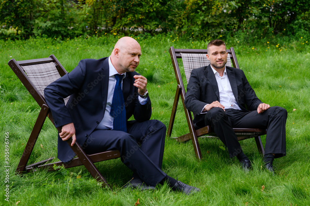 Two partners sit in armchairs and think Two partners sit in armchairs and think