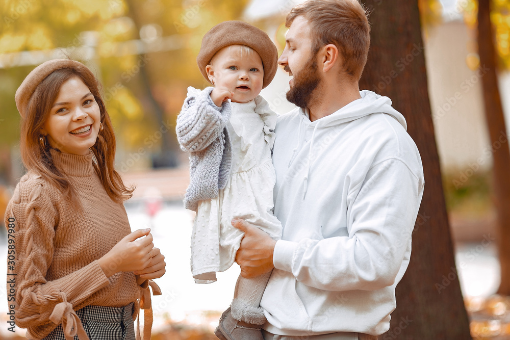 Family in a autumn park. Woman in a brown sweater. Cute newborn little girl with parents