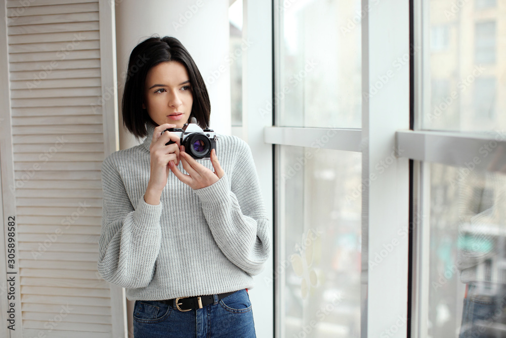 portrait of a beautiful hipster girl with a camera standing by the window portrait of a beautiful hipster girl with a camera standing by the window
