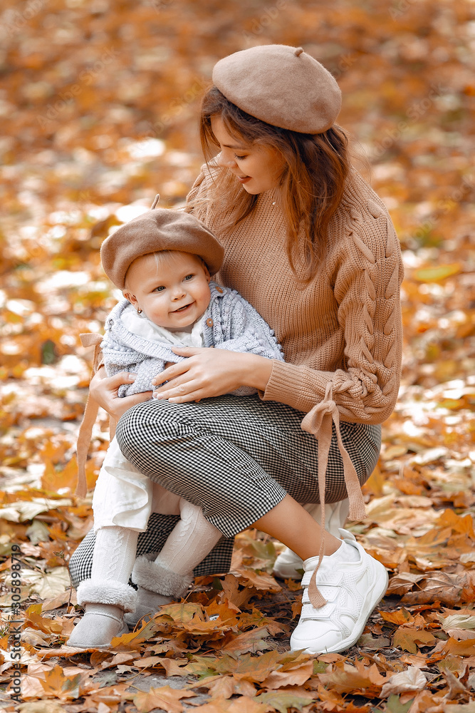 Fashionable mother with daughter. Family in a autumn park. Little girl in a brown hat Fashionable mother with daughter. Family in a autumn park. Little girl in a brown hat