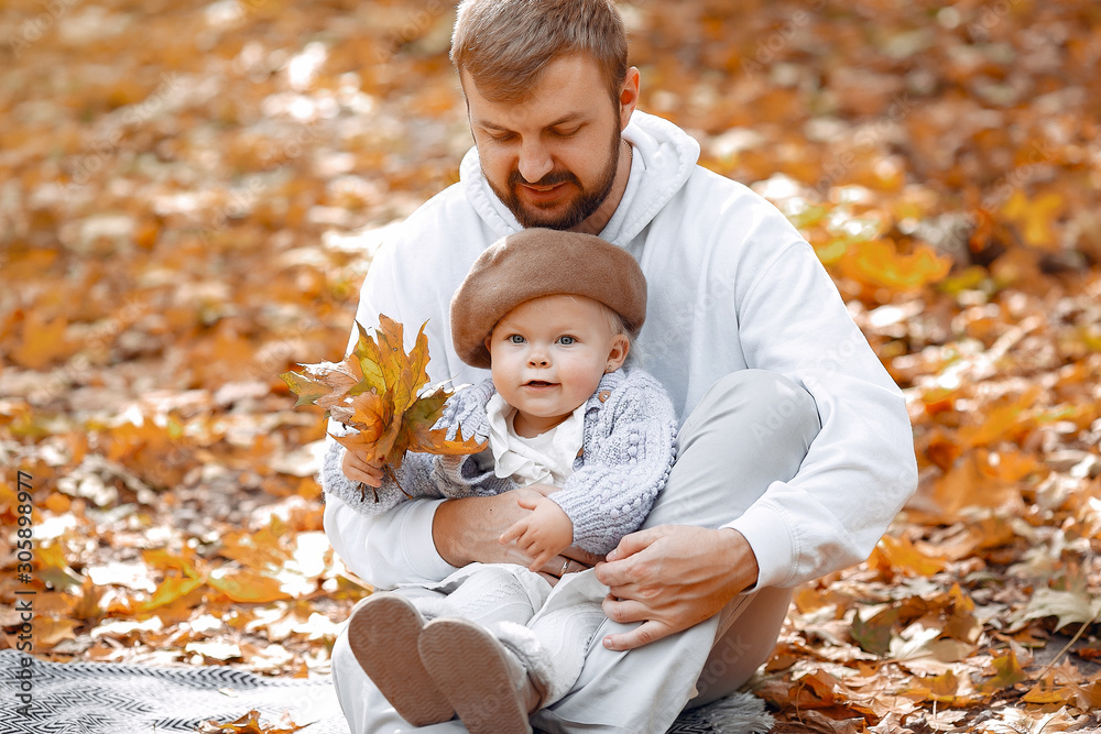 Family with cute daughter. Father in a gray sweater. Handsome man playing in a park with daughter. Family with cute daughter. Father in a gray sweater. Handsome man playing in a park with daughter.