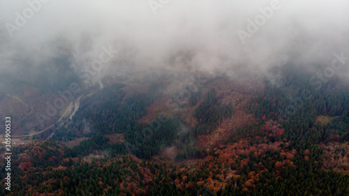 View from a drone to forest, river and village through the fog.