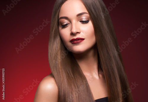 Woman beautiful make up face female red lops long smooth hair red dark background
