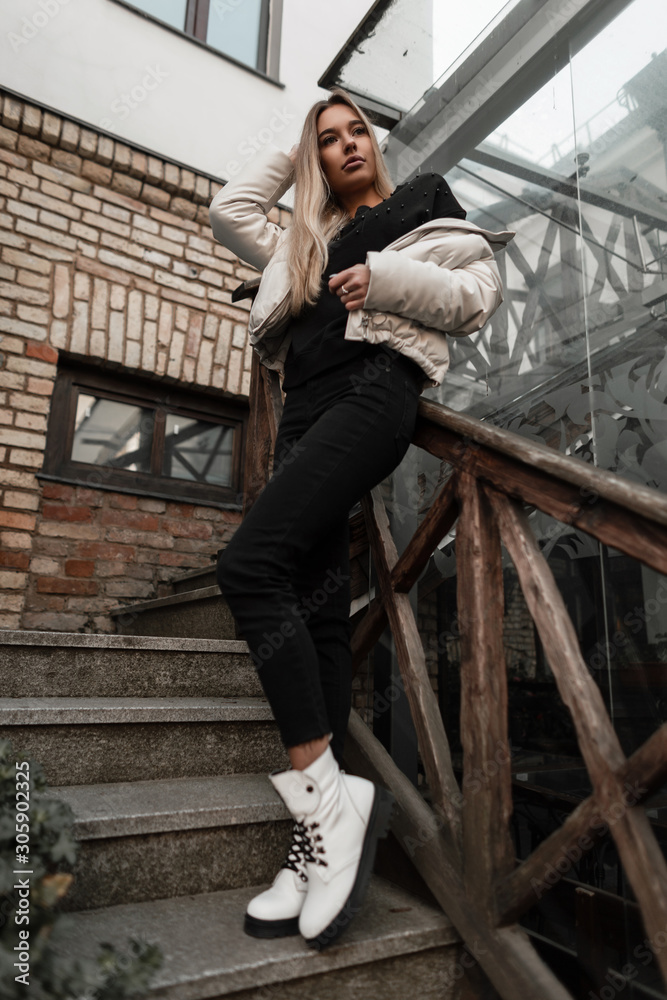 Urban fashion model of a cute young woman in spring-autumn clothes in  trendy boots posing