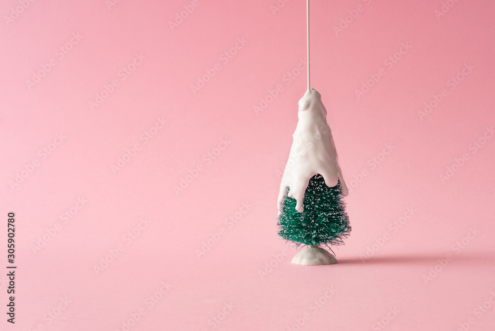 Fototapeta Christmas tree with white dripping paint as snow against pastel pink background. Minimal creative holiday concept.