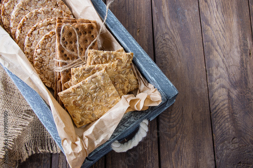 Useful dietary grain loaves (rye, buckwheat, wheat) in an old wooden box on a wooden background. vertical version