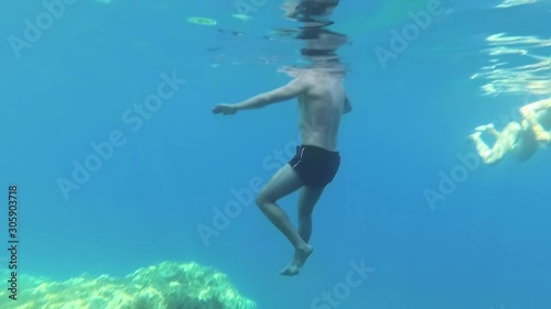 Wallpaper Mural underwater shot in the blue clear sea. A man in swimming trunks in deep water moves his arms and legs to stay on the surface, slow motion Torontodigital.ca