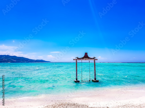 Gili Islands, Indonesia, Asia. Beautiful beach crystal clear water and white sand in an exotic tropical destination. Famous wooden water swing. Popular instagram location.  photo