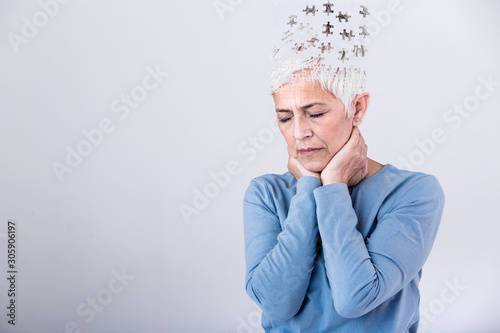 Memory loss due to dementia. Senior woman losing parts of head as symbol of decreased mind function. Senior woman losing parts of head feeling confused as symbol of decreased mind function. photo