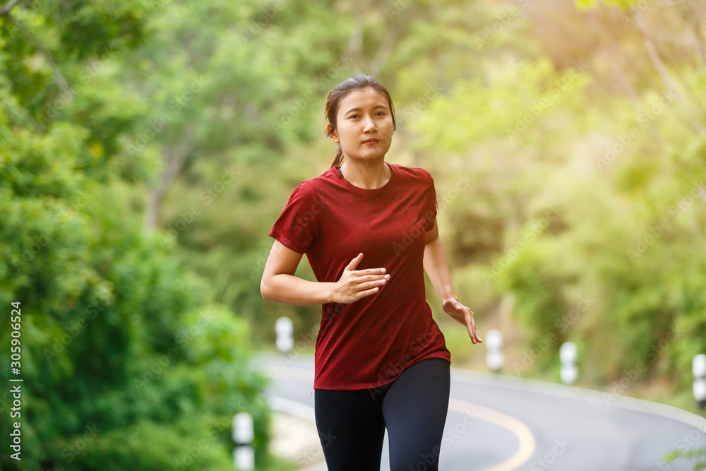 Front of woman runner and runing at the road surround with green forest. Front of woman runner and runing at the road surround with green forest.