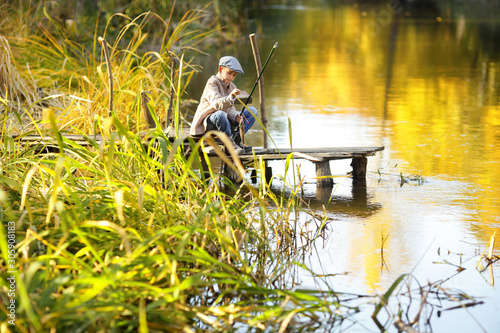 Boy is fishing at sunset on the lake © azhurfoto