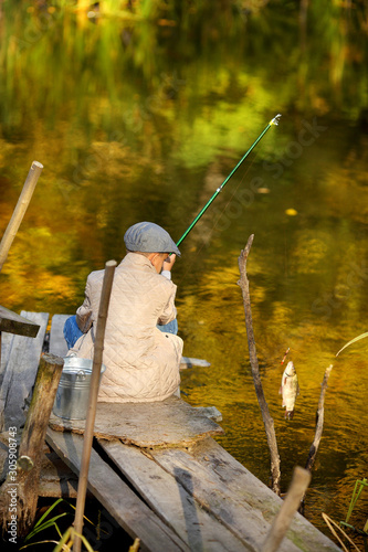 Kid fishing in a river, sitting on a wood pontoon © azhurfoto