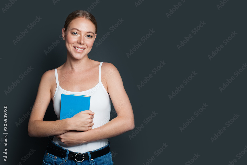 Friendly young woman holding book on gray background Friendly young woman holding book on gray background