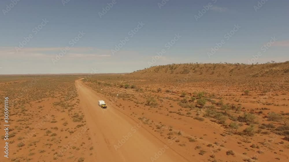 Yellow car towing a white caravan on a dirt road Yellow car towing a white caravan on a dirt road