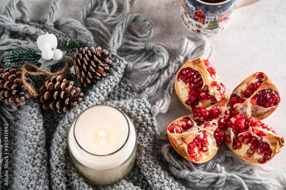 pomegranate and candle, on a light marble backdrop, cup of tea and Christmas ornament on background pomegranate and candle, on a light marble backdrop, cup of tea and Christmas ornament on background