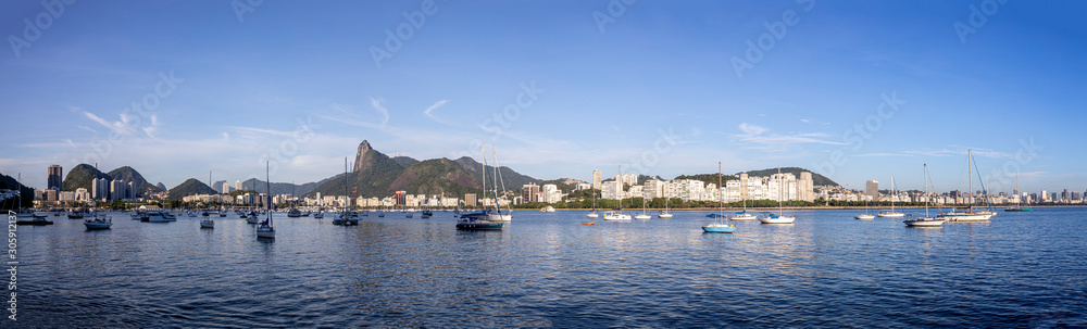 Wide panorama view of Rio de Janeiro at sunrise with the Corcovado mountain in the background and pleasure boats scattered in the Guanabara bay in front seen from the Urca neighbourhood