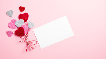 Valentine day concept. Creative layout with balloon made of valentine hearts and blank paper card on pink background. Flat lay, top view.