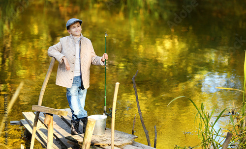 Boy with a fishing net is leaning on a wooden dock railing