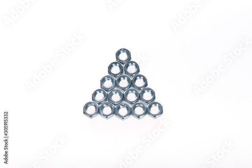 Metal nuts laid out in the form of a triangle on a white background
