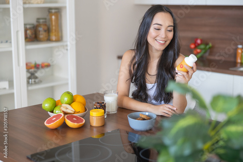 Young woman taking a nutritional supplement at breakfast photo