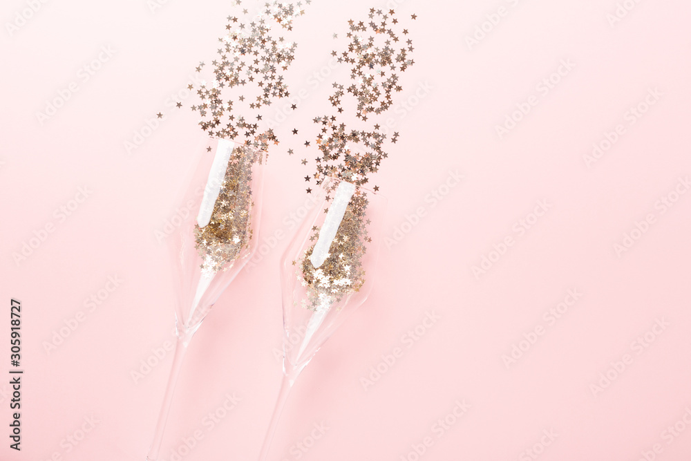 Obraz premium Christmas flat lay. Champagne glasses and gold decoration on pink background - Image
