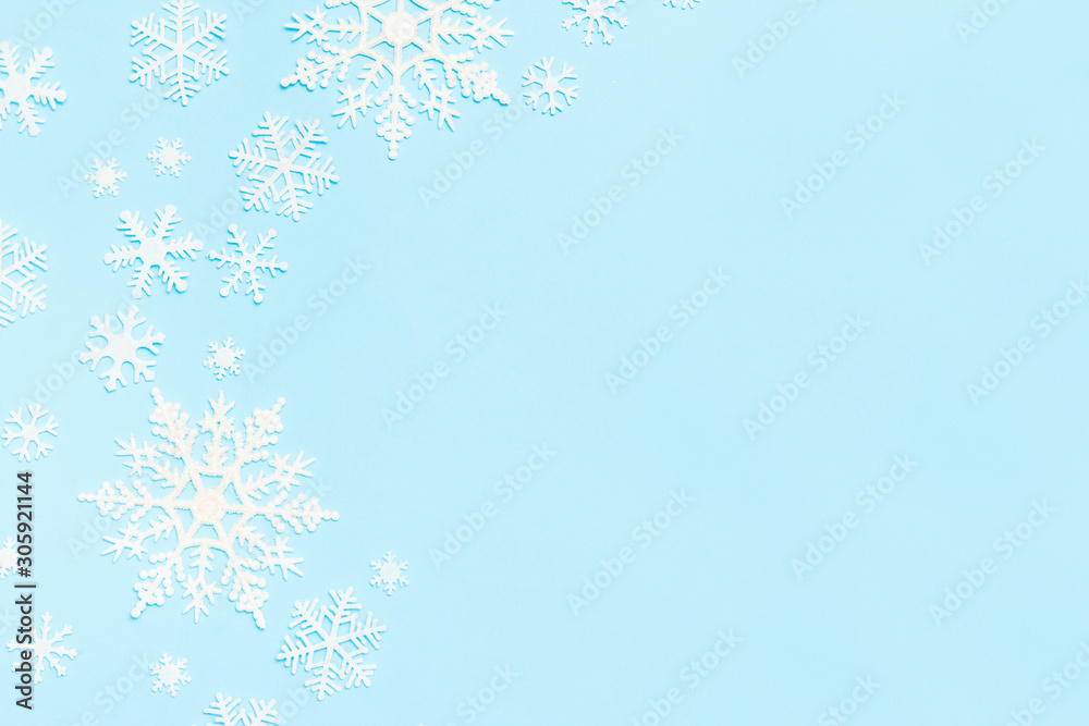 Christmas or winter composition. Snowflakes decoration on blue pastel background. Flat lay, top view, copy space.