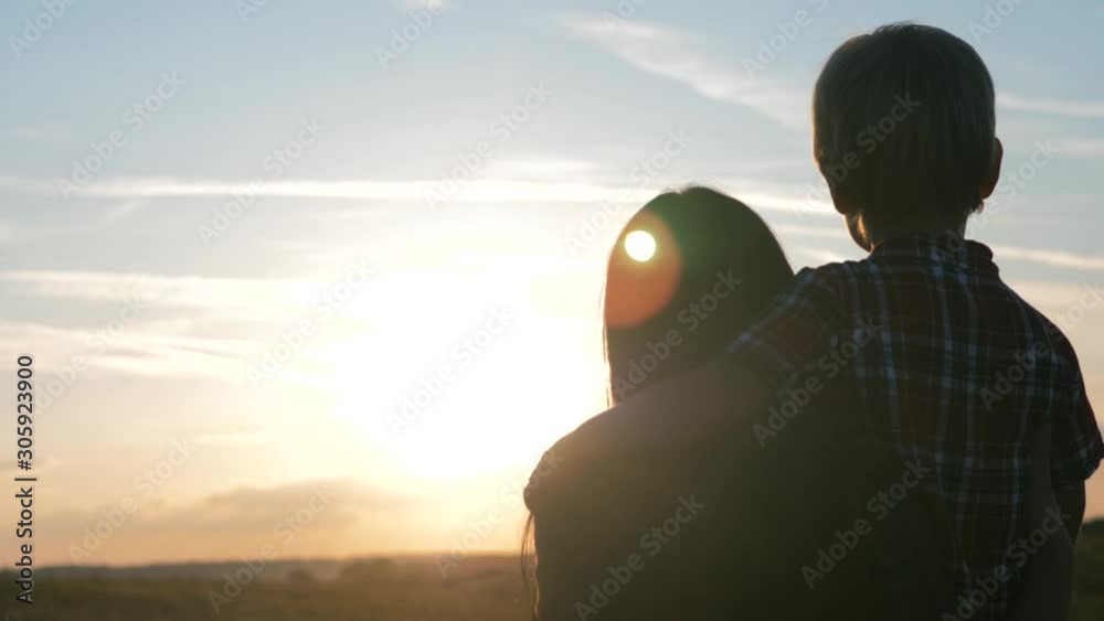 happy family mom and son a sunset slow motion video concept. back view Mother girl and son boy playing on nature outdoors at lifestyle the sunset time .Concept of friendly sunset family