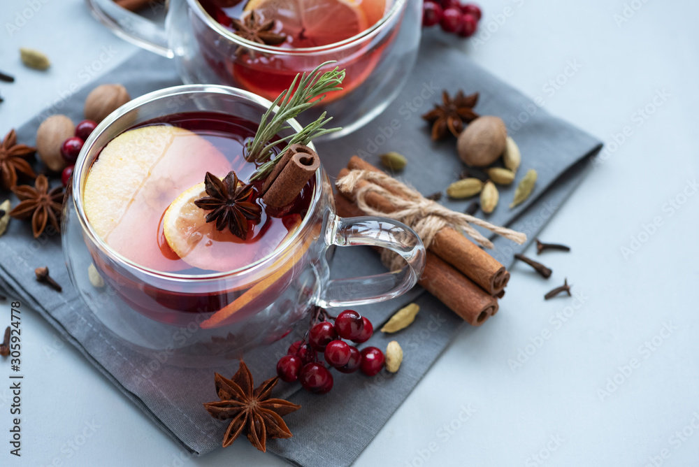 Two cups of Christmas mulled wine or punch with spices and lemon slices on gray wooden background. Christmas or New Year celebration concept Two cups of Christmas mulled wine or punch with spices and lemon slices on gray wooden background. Christmas or New Year celebration concept