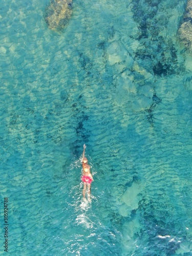aerial view of joung man swiming on cristal clear waters on a beach of mallorca. Concept of holiday, summer, travel, tourism and relax
