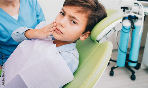 little boy with teeth pain sitting to dental chair. toothache  child sadly looking at the camera