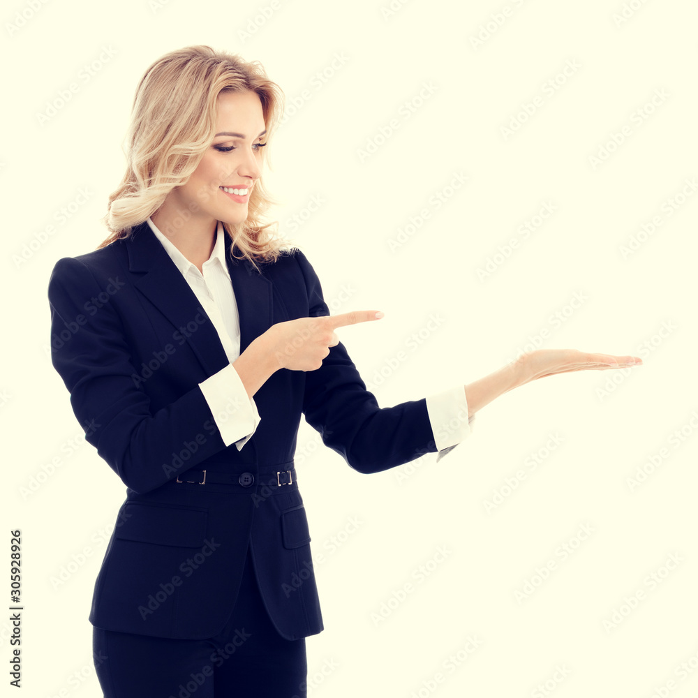 Happy smiling young businesswoman in confident style black suit, showing something, some product or copy space for advertise slogan or text message. Caucasian blond model in business success concept. Happy smiling young businesswoman in confident style black suit, showing something, some product or copy space for advertise slogan or text message. Caucasian blond model in business success concept.