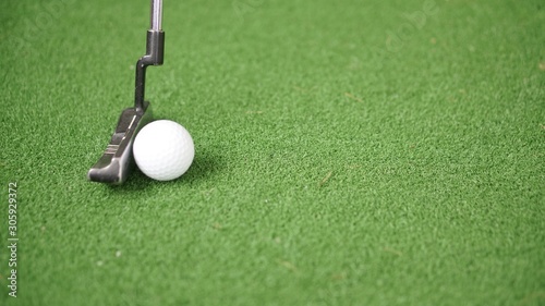 Image of golf putter and golf ball on green grass