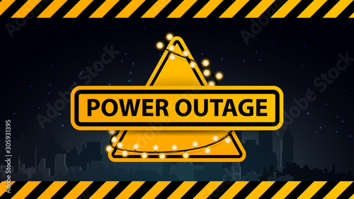 Power outage, yellow warning logo wrapped with a garland on the background of the city without electricity