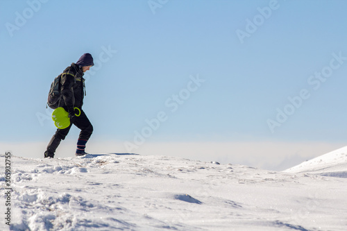 Silhouette of alone tourist walking on snowy mountain top enjoying view and achievement on bright sunny winter day. Adventure, outdoors activities and healthy lifestyle concept.