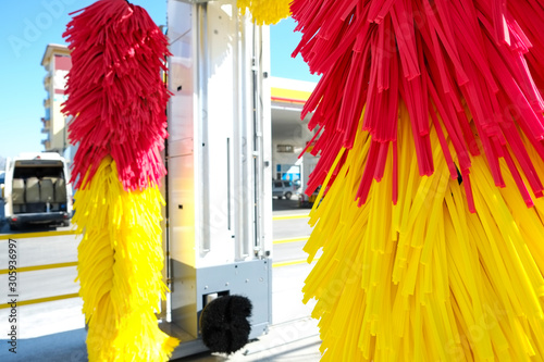 Fototapeta Naklejka Na Ścianę i Meble -  Empty outdoor self service car wash at gas station premises. Colorful red and yellow rotating carwash brushes. Close up, copy space, background.