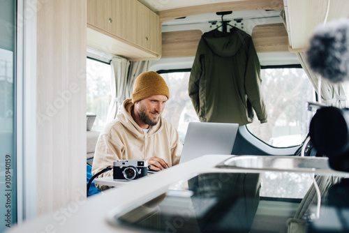 Fototapeta Work and Travel with Campervan in Australia young man is working in his van duri